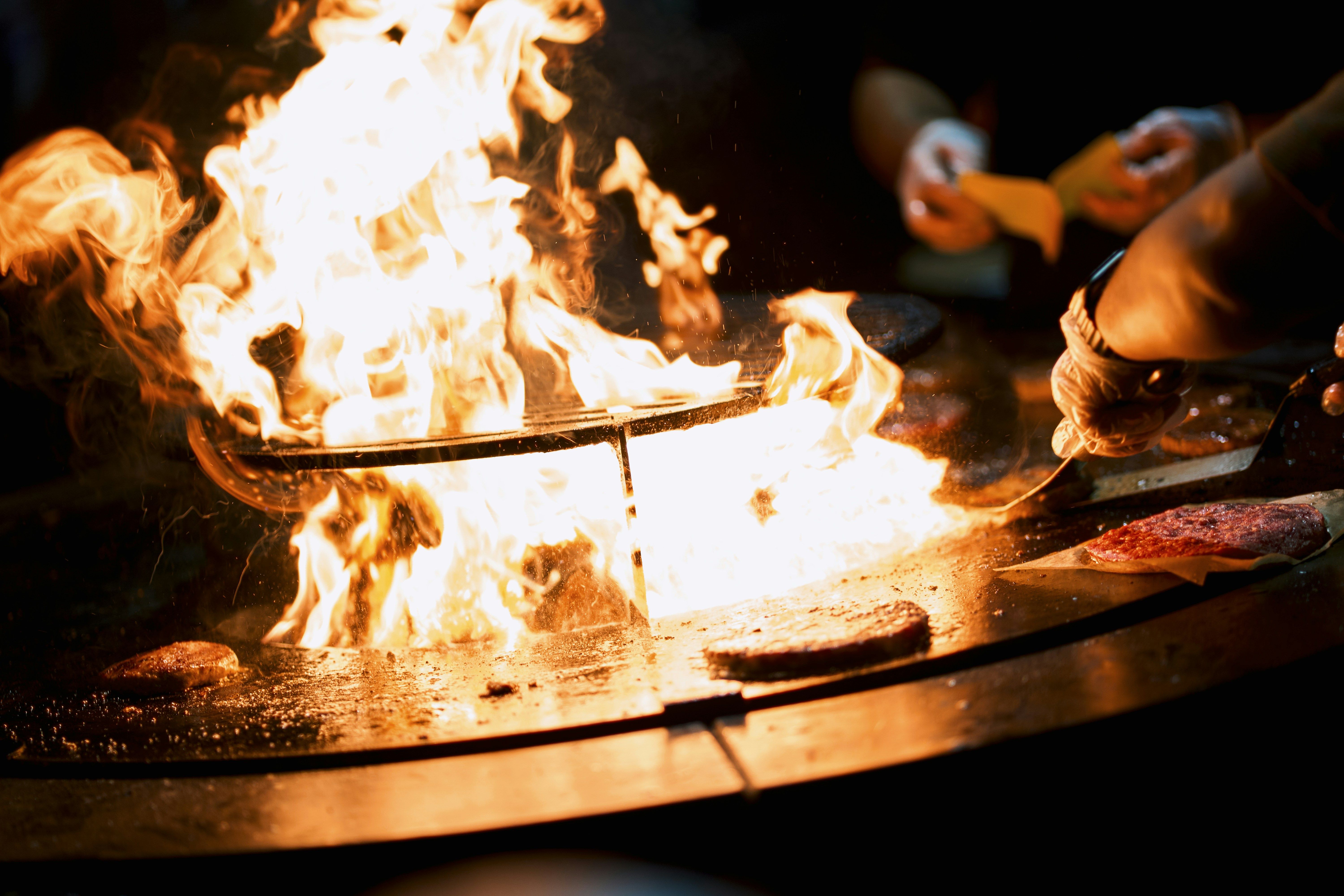 Carnes de hamburguesa sobre la parrilla con la llama encendida